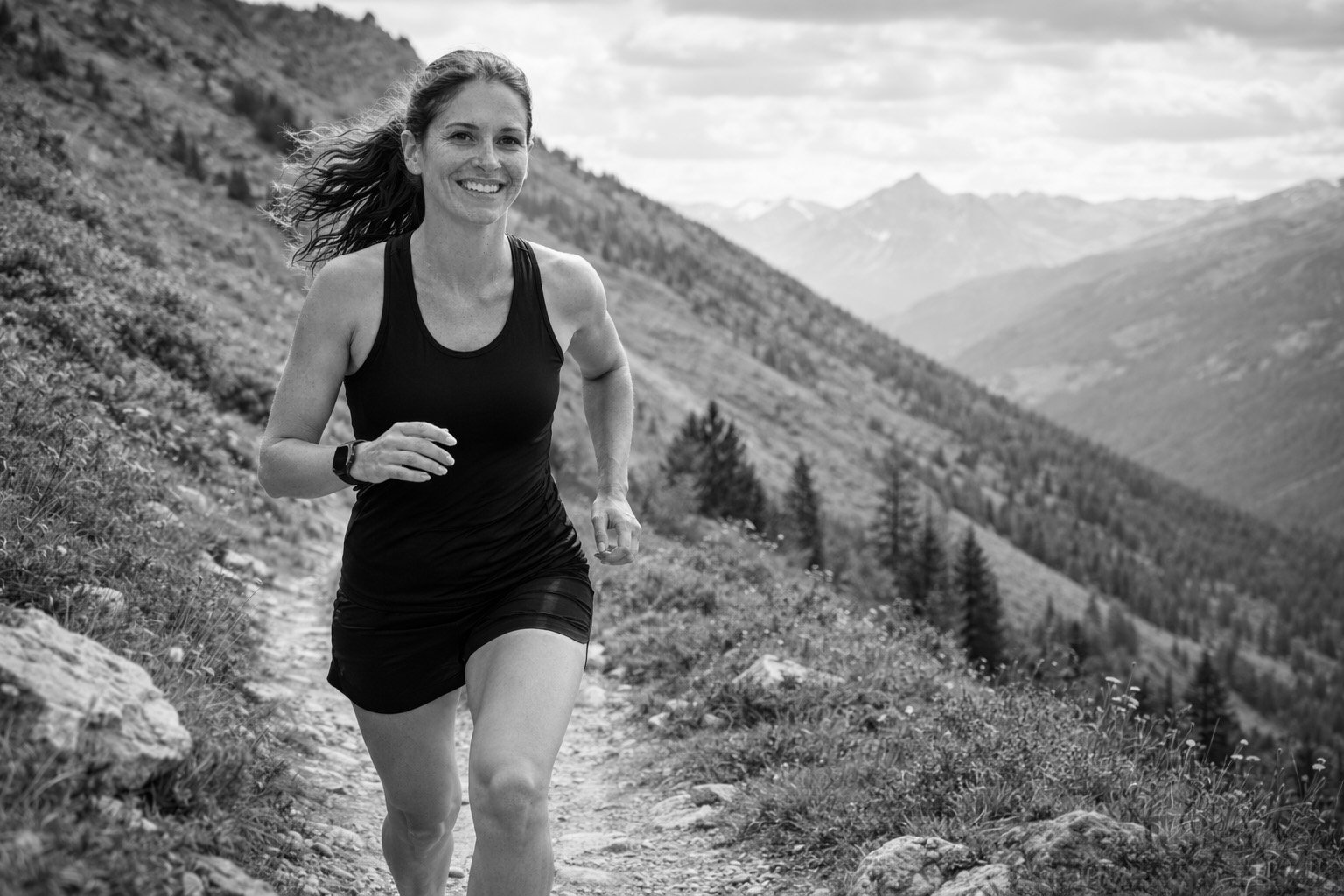 Fit middle-aged woman trail running on a mountain path, representing outdoor fitness, endurance, and all-round strength after 45.